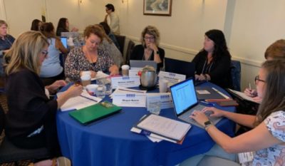 Several people sitting around a table at a workshop and taking notes