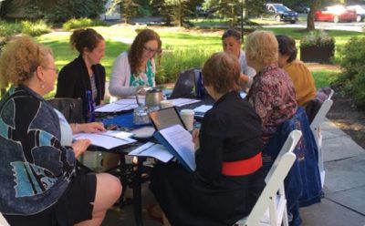 Several people sitting around a table discussing a topic and taking notes